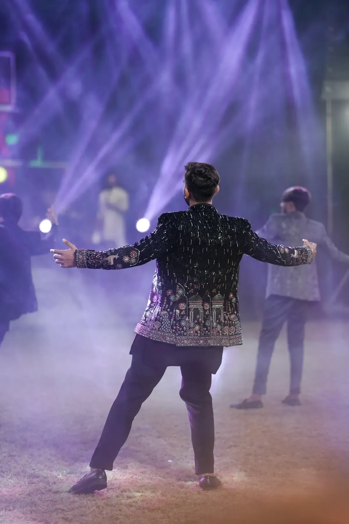Groom dancing during a wedding celebration under purple lights